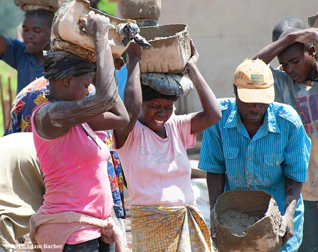 editorial photographer from portland oregon in rwanda - woman carrying cement